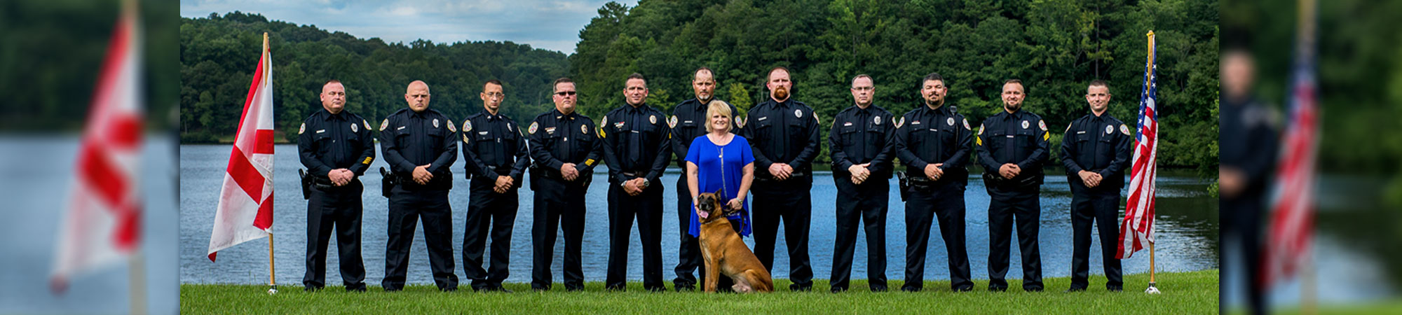 police officers and police dog lined up in front of lake